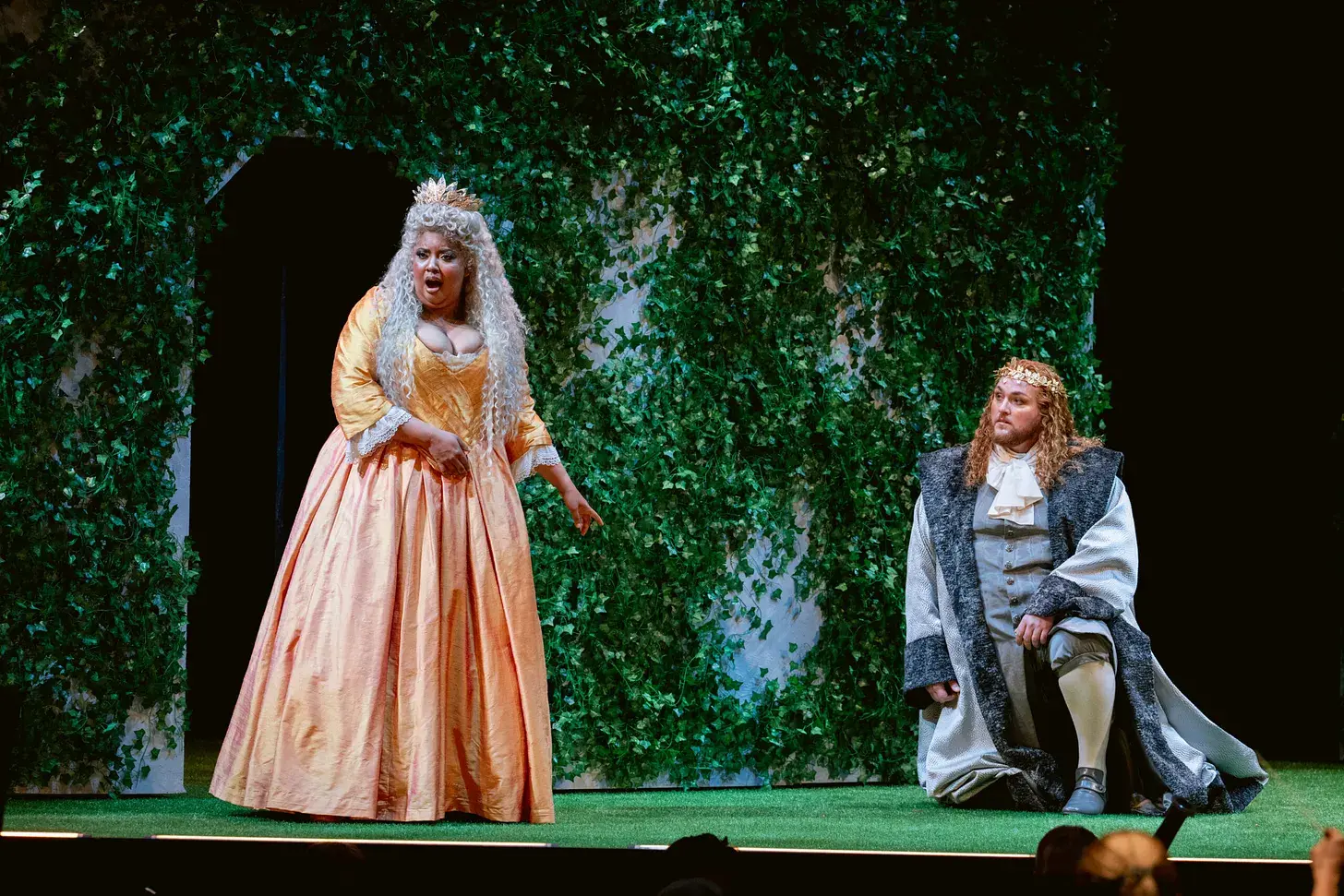 Merola Opera Program production — a soprano in a peach gown performs opposite a crowned king on an ivy-covered set